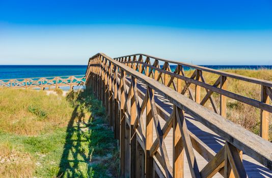 Wooden footbridge over the sand dunes to the beach of Alcudia bay on Majorca, Spain Mediterranean Sea