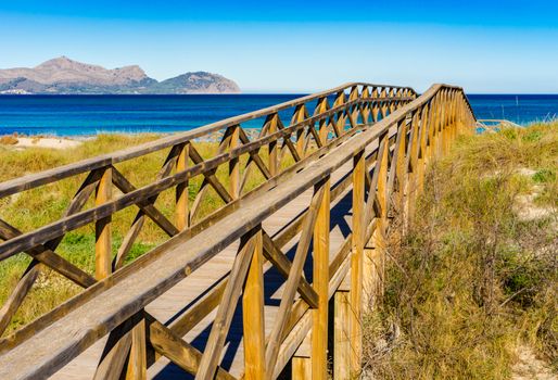 Wooden footbridge over sand dunes on Majorca island at the bay of Alcudia, Spain