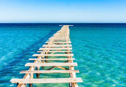 View of damaged wooden jetty with blue sea water
