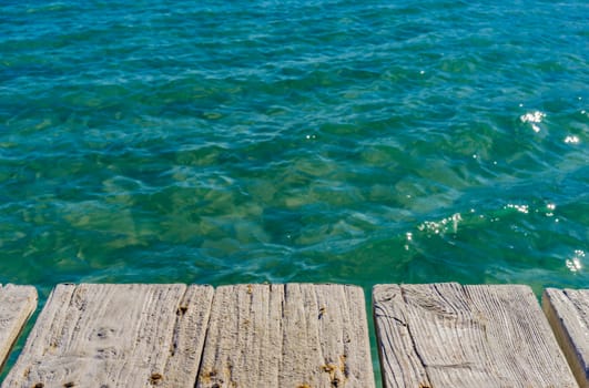 Wooden jetty on blue sea water background