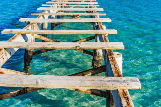 Close-up of damaged wooden jetty with blue sea water