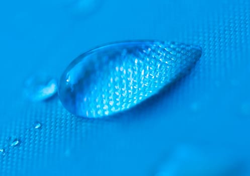 Close-up of a drop of water on a blue background.