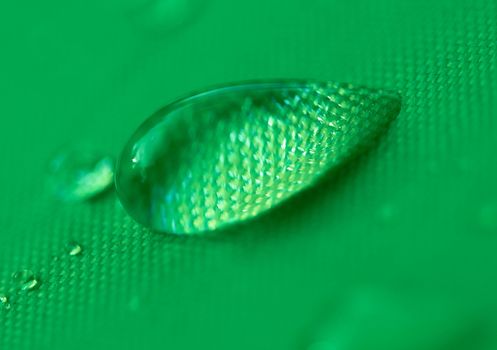 Close-up of a drop of water on a green background.