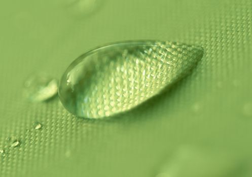 Close-up of a drop of water on a green background.