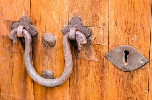 Close-up of door knocker and keywhole of old wooden front door 