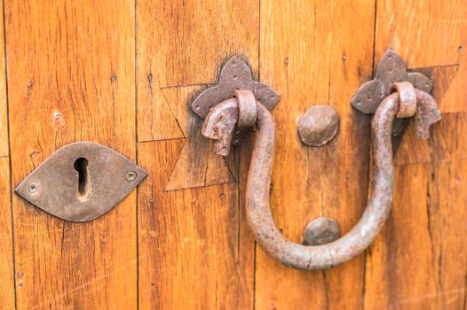 Rusty door knocker and keyhole of old wooden door