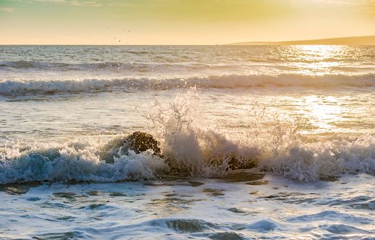 Beach surf wave breaking on rocky coast