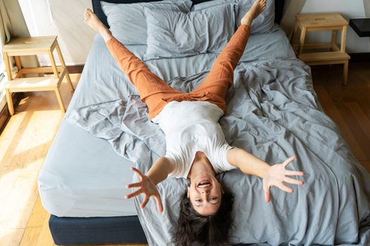 Beautiful young brunette girl fooling around on the bed. View from above. Good mood.