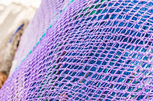 Close-up of purple and blue fish net heap, maritime background texture