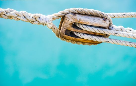 Detail image of wooden pulley with ropes of classic sailing yacht