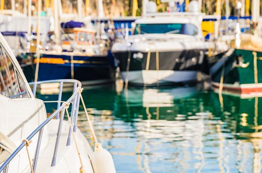 Luxury yachts moored at harbor with detail view of boat deck and railing of motor yacht