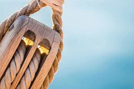 Nautical pulley with ropes of a classic sailing boat and blue sea water 