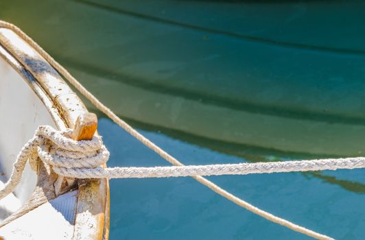 Detail view of nautical rope cleat and mooring line on old fishing boat deck