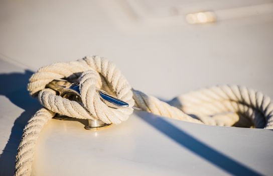 Detail image of tied knot of nautical rope on cleat of boat deck