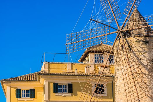 Close-up of historic windmill and modern house at background
