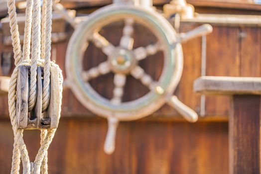 Pulley and wooden helm wheel on old sailboat deck