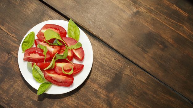Sliced tomatoes with lettuce on a white plate. Healthy eating concept. High quality photo