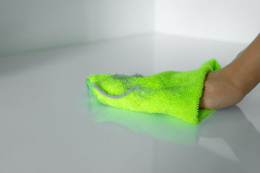 Cleaning the house. Wipe off the dust with a green rag from a dirty surface. A lot of dust on a rag