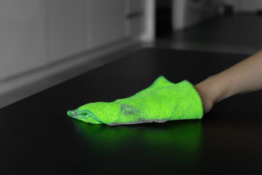 Cleaning the house. Wipe off the dust with a green rag from a dirty surface. A lot of dust on a rag