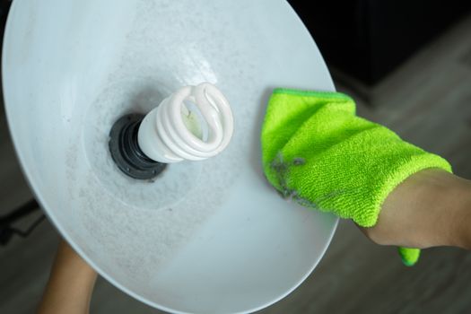 Cleaning the house. Wipe off the dust with a green rag from the floor lamp. Energy saving light bulb. A lot of dust