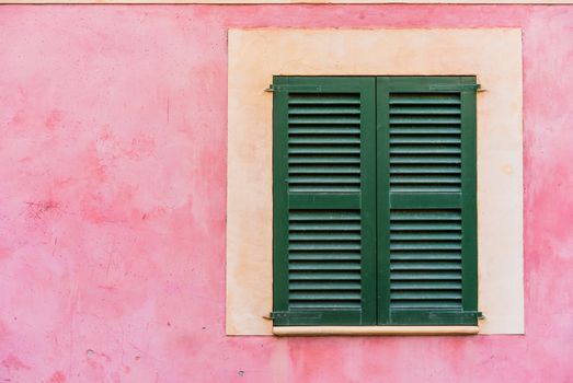 Detail view of green window shutters and plaster wall