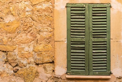 Detail view of green closed wooden window shutters and rustic wall