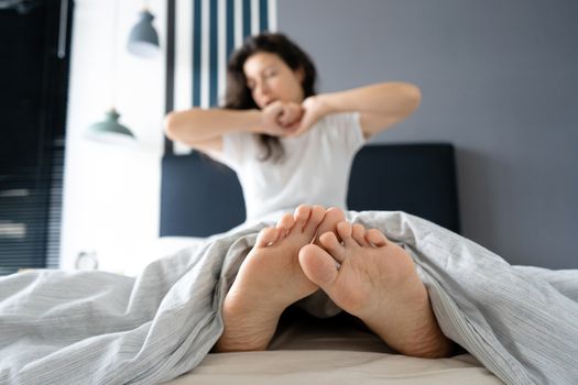 Beautiful girl wakes up in a good mood in a stylish apartment. View from the feet.