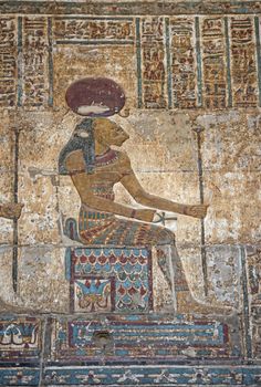 Hieroglypic colourful carving paintings on wall at the ancient egyptian temple of Khnum in Esna with god Sekhmet