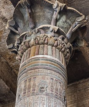 Columns in the ancient egyptian temple of Khnum at Esna with painted hieroglyphic carvings showing the god Bes