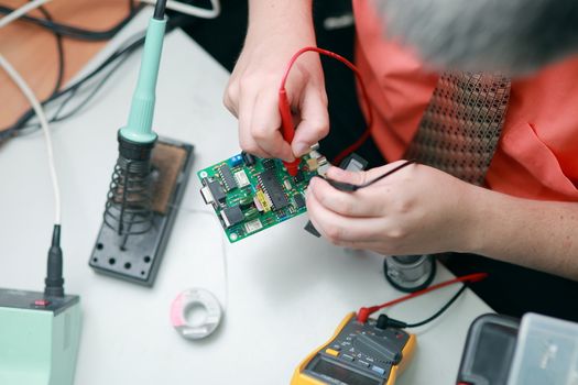 The hands of a man are engaged in the repair of tools, the manufacture of electronics Services, Manual assembly of the soldering circuit board. High quality photo