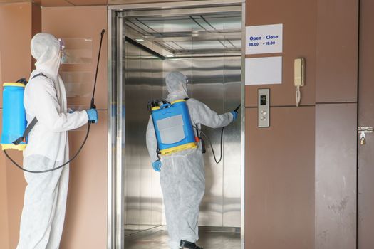 Professional  male worker In protective clothing and masks are spraying disinfectants, cleaning, controlling virus and bacteria in the contaminated area After the spread of coronavirus or COVID-19