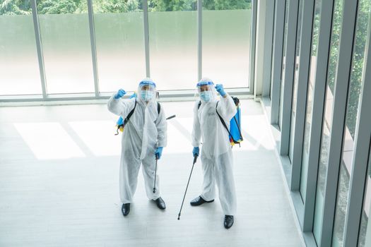 Professional  male worker In protective clothing and masks are spraying disinfectants, cleaning, controlling virus and bacteria in the contaminated area After the spread of coronavirus or COVID-19