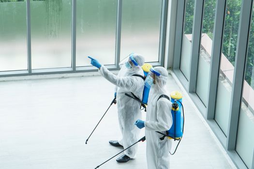 Professional  male worker In protective clothing and masks are spraying disinfectants, cleaning, controlling virus and bacteria in the contaminated area After the spread of coronavirus or COVID-19