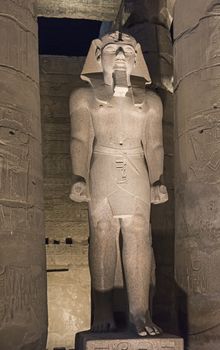 Ancient statue of Ramses II at Luxor Temple lit up in nighttime