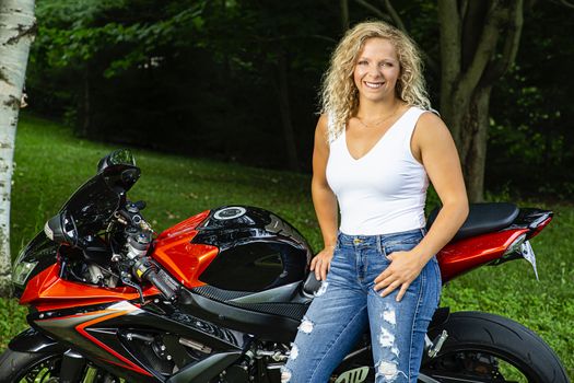 Cute blond woman standing beside a sport motorcycle