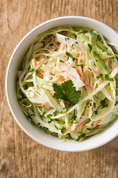 Coleslaw salad in white bowl on wooden table