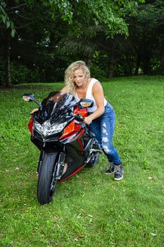 twenty something blond woman pushing a sport motorcycle