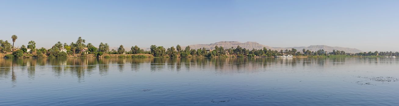 Panoramic landscape rural countryside view of large river nile in arid environment showing luxor west bank