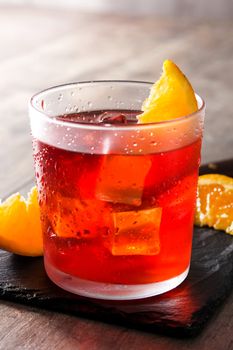 Negroni cocktail with piece of orange on wooden table
