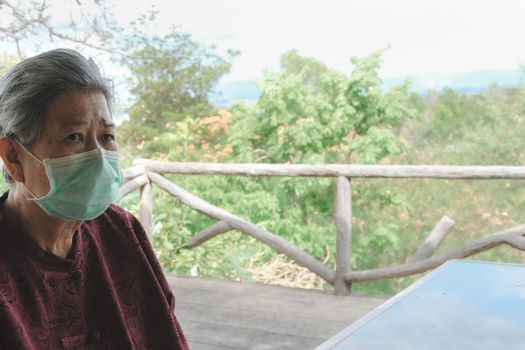 old elder woman wearing facial medical mask resting in garden. asian elderly senior relaxing indoors. female leisure lifestyle