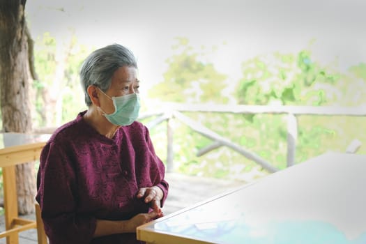 old elder woman wearing facial medical mask resting in garden. asian elderly senior relaxing indoors. female leisure lifestyle