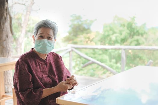 old elder woman wearing facial medical mask resting in garden. asian elderly senior relaxing indoors. female leisure lifestyle