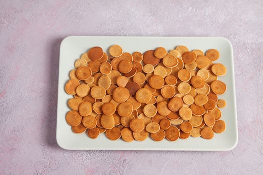 Trendy homemade breakfast, pancake cereal, mini pancakes on light plate on pink concrete background