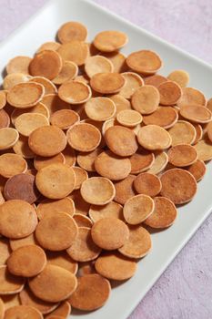 Trendy homemade breakfast, pancake cereal, mini pancakes on light plate on pink concrete background