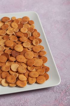 Trendy homemade breakfast, pancake cereal, mini pancakes on light plate on pink concrete background