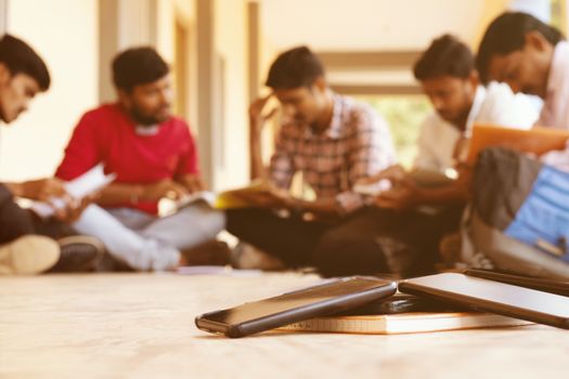 Selective focus on mobiles, group of students busy in reading by avoiding smartphone from distraction - Concept of young people addicted to cellphones while reading