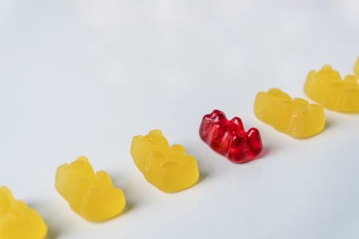 Row of yellow and red jelly bears candy on a white background.