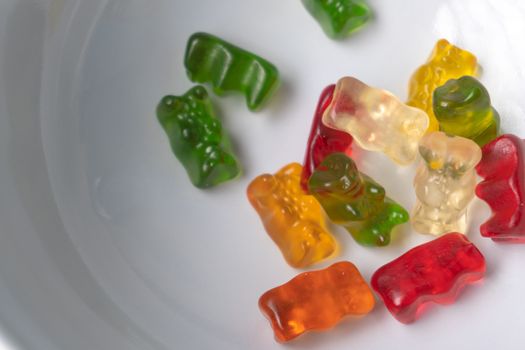 Pile of multicolored jelly bears candy on a white background.