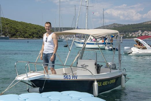Croatia, Hvar - June 2018: Caucasian man, mid 40's , stands on the deck of a small boat
