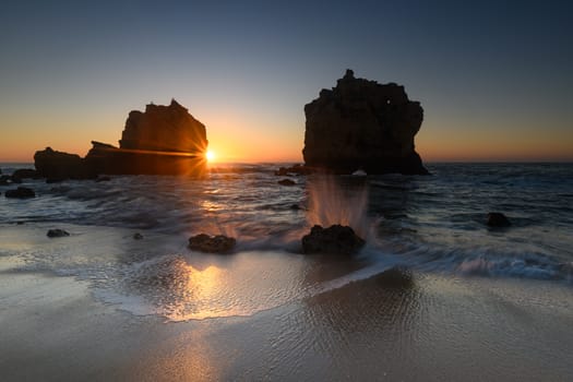view of coastal rocks at sunrise with splashing waves